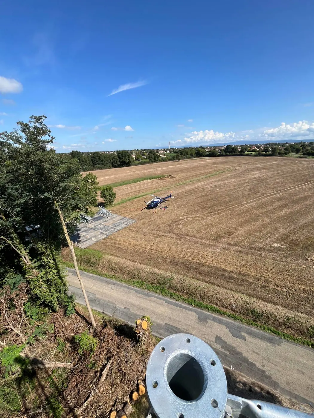 Vue depuis le sommet d'un pylône, hélicoptère posé dans le champ