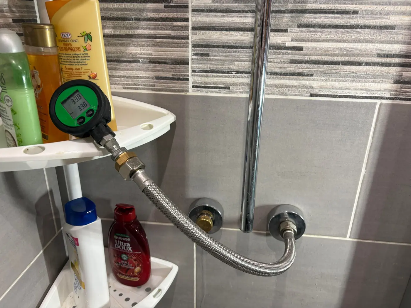 Manomètre numérique raccordé à l'arrivée d'eau d'une douche